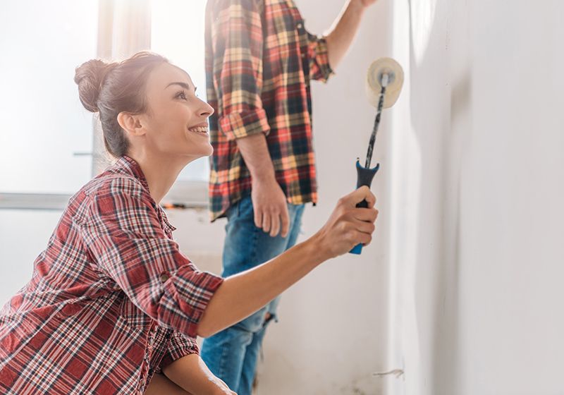 Una pareja pintando la pared.