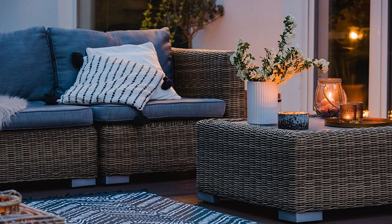 Primer plano de una terraza exterior donde se ve parte de un sofá y la mesa de centro.